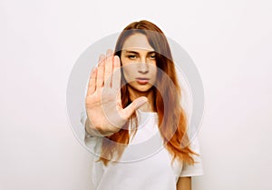 Portrait of a serious young redhair woman standing with outstretched hand showing stop gesture