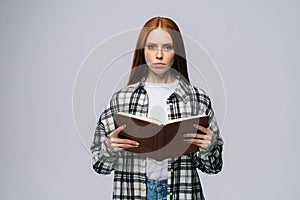 Portrait of serious young woman college student holding opened books and looking at camera