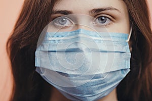 Portrait of serious young woman face in a protective medical mask on colored studio background, girl`s sad eyes, concept of healt