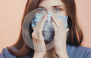 Portrait of serious young woman face in a protective medical mask on colored studio background, girl`s sad eyes, concept of healt