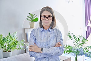 Portrait of serious young woman looking at camera with crossed arms