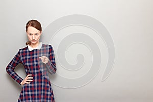 Portrait of serious young woman pointing with index finger at you