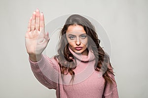 Portrait of a serious young woman standing with outstretched hand showing stop gesture isolated over white background