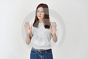 Portrait of a serious young woman standing with outstretched hand showing stop gesture isolated over white background