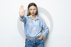 Portrait of a serious young woman standing with outstretched hand showing stop gesture isolated over white background