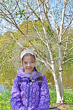 Portrait of the seven-year-old girl against the background of the blossoming birch of useful Himalaya Betula utilis D.Don
