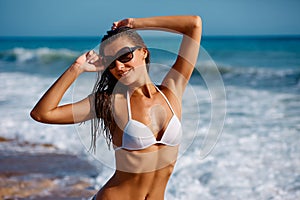 Portrait of sexy beautiful tanned woman posing in colorful swimwear bikini at the sea coast. Exotic country travel and rest