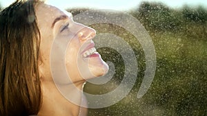 Portrait of a sexy, beautiful young blonde girl, under a light summer rain, in the sun rays, on a green meadow. The girl