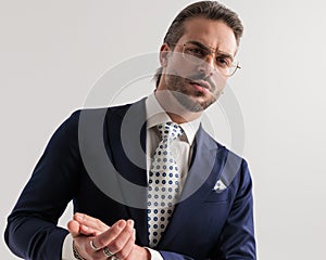 portrait of sexy elegant man with glasses looking forward and rubbing palms