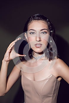 portrait of a sexy fashionable makeup artist girl in a white skirt shows a round powder box standing in the studio.