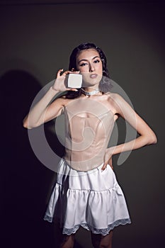 portrait of a sexy fashionable makeup artist girl in a white skirt shows a white square box of powder standing in the