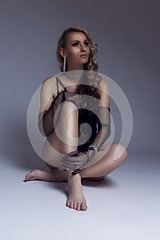 Portrait of Sexy Long hair Alluring Young Caucasian Woman in Sensual Body Suit Posing in Studio on Floor