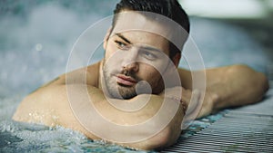 Portrait of sexy man enjoying in whirlpool bath. Handsome guy relaxing in pool