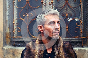 Portrait of a man in wolf fur and ornamental medieval window on background