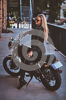 Portrait of sexy matyre female biker next to brick building