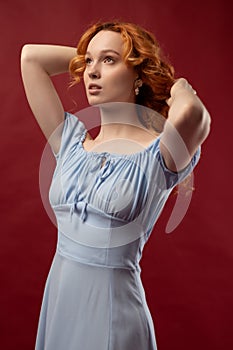 Portrait of a sexy red-haired woman with long hair on a red background.