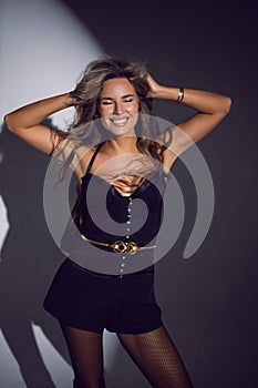 portrait of a sexy woman in a black corset, shorts and boots stands in the studio on a white cyclorama with a light spot