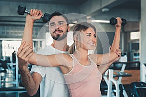 Portrait of woman in fitness gym training with dumbbell equipment., Couple caucasian are working out and training together in