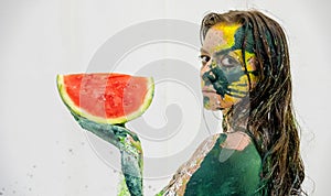 Portrait of a sexy, yellow, green painted woman, like a cat, holding a fresh juicy red watermelon slice in her hand, bodypainting photo