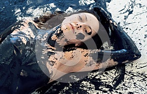 Portrait of a sexy young brunette woman with dots of black color paint. Decorative, creative expressive abstract face and body