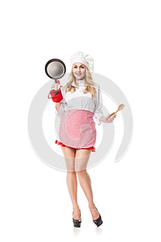 Portrait of young woman with frying pan and spoon in high heels