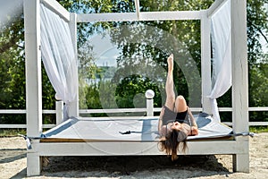 portrait of sexy young woman wear black dress lying white beds gazebo near beach