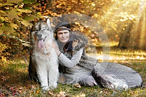 Portrait of a shaman woman with a big Alaskan Malamute dog in the forest