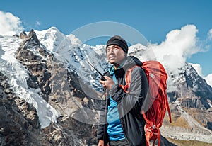 Portrait of Sherpa man with backpack using walkie-talkie for calling rescue helicopter with Mera peak 6476m background.High