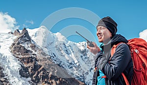 Portrait of Sherpa man with backpack using walkie-talkie for calling rescue helicopter with Mera peak 6476m background.High