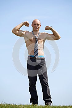 Portrait of shirtless bald young man wearing tie holds his arms