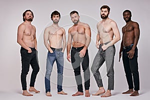 Portrait of shirtless diverse men posing seriously at camera, sexy guys in jeans