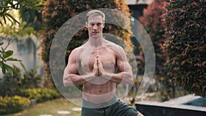 Portrait of shirtless man with muscular body doing yoga exercises in garden