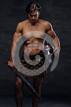 Portrait of shirtless muscular male holds silver gladiator helme
