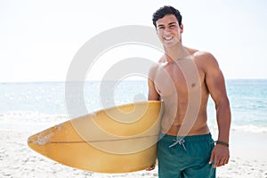 Portrait of shirtless muscular man holding surfboard at beach