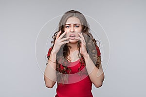 Portrait of shocked afraid woman looking with having wide open mouth gesturing palms, standing gray background