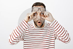 Portrait of shocked amazed funny male coworker, holding glasses on forehead and pulling eyelids, staring with popped