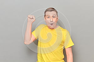 Portrait of shocked amazed rebellious mature man raising fist up