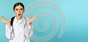 Portrait of shocked female doctor, worried healtcare worker in white robe, looking concerned at patient, standing over