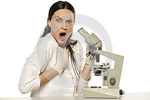 Portrait of shocked female scientist with microscope