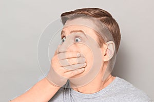 Portrait of shocked frightened man covering mouth with hand