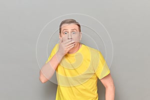 Portrait of shocked frightened mature man covering mouth with hand