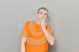 Portrait of shocked frightened mature man covering mouth with hand