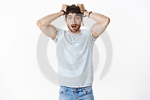 Portrait of shocked guy in stupor dropping jaw astomished pulling hair out of head being impressed deeply standing photo