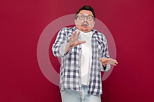 Portrait of shocked handsome middle aged business man in casual checkered shirt and eyeglasses standing and looking at camera with