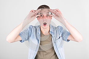 Portrait of a shocked man in eyeglasses looking at camera while raised up glasses.  over white background