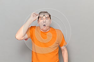 Portrait of shocked man raising his glasses to forehead and screaming