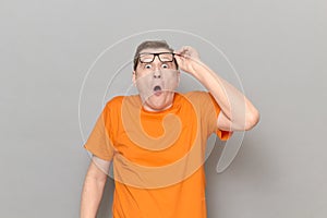 Portrait of shocked man raising his glasses to forehead and screaming