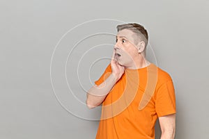 Portrait of shocked man touching cheek with one hand and screaming