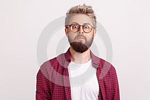 Portrait of shocked by news bearded man freelancer in eyeglasses and checkered shirt surprisingly