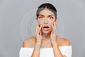 Portrait of shocked pretty young woman touching her face